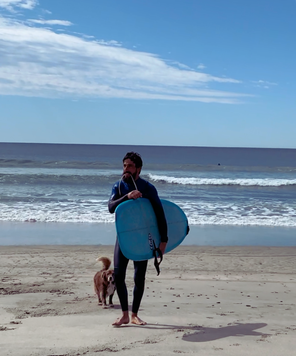 Longboard surf Lisbon – surfer walking along a Costa da Caparica beach with a longboard.